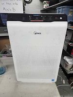 Front view of Winix air purifier showing brand logo and perforated grille