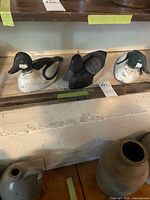 Three wooden duck decoys on shelf showing overall lot and paint wear