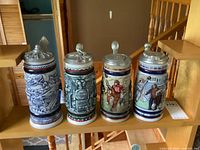 Group shot of all four lidded steins on shelf