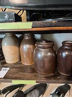 Shelf view of four stoneware crocks showing colors and two lids