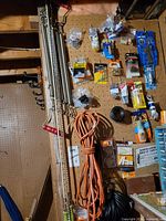 Pegboard with packaged fasteners, adhesives, coil-spring bars, extension cord
