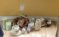 Group shot of all porcelain teaware, decorative bowl, figurine, candles, salt shaker, condiment holder and vase on floor
