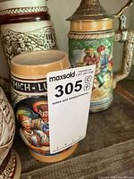 Two steins showing painted figural and relief designs with pewter lids