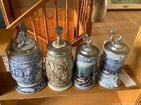 All four Avon wildlife beer steins lined up showing designs and pewter lids