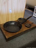 Three cast iron pans resting on wooden dolly