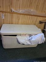 Front and side view of white Coleman Marine 100 cooler, lid partially open with gift bag protruding