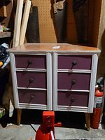 Front view of six-drawer dresser showing white frame, purple drawers, brass pulls, tapered legs