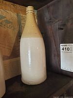 Three stoneware ginger beer bottles showing brown tops and cream bodies, one branded James Thompson Kingston