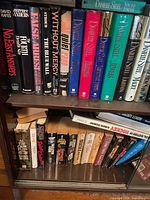 Two shelves showing hardcover Danielle Steel titles and other thrillers plus lower shelf of paperbacks