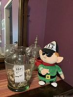 Front view showing green glass vase with stones, pressed glass lamp and plush elf