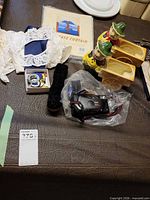 Overview of all items laid out: camera in bag, planters, packaged curtain, lace doilies, jewellery tin, cleaning brush