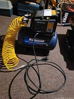 Full view of compressor with attached yellow hose and power cord