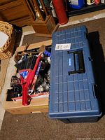 Tool box closed next to cardboard box of hardware