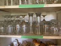 Multiple sizes of upside-down stemware on shelf, showing gold floral bands