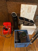 Group shot of heater, gasoline tank, Styrofoam cooler, planter, crate with pots and trays