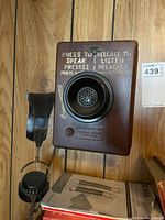 Front view showing wood case, bakelite mouthpiece, bilingual instructions, hanging earpiece