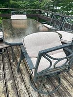 Top view of glass table and swivel chair showing frame, cushions, wear