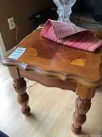 Oblique view of one table showing inlaid top, carved legs, finish