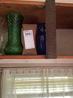 Shelf with four vases: clear, green, tan, blue