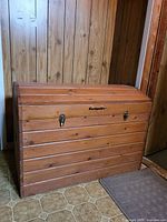 Front view showing slatted wood, brass-tone latches and handle
