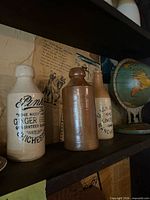 Shelf view showing three stoneware bottles and globe