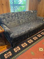 Full front view of sofa placed against wood panel wall
