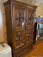 Front view showing carved paneled doors and lower drawer