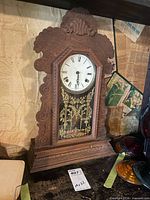 Full view of wooden gingerbread mantel clock on shelf