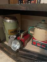 Thermos flask, flashlight, teapot on Mackintosh tin visible on shelf