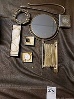 Full lot overview showing pocket watch, necklace box, ornate frame, wall mirror and cigarette case