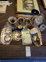 Group shot of entire lot including silverplate tray set, goblets, candlestick, jars, brass stand and clock plaque