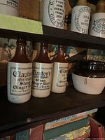 Three Clayton’s brown-top stoneware ginger beer bottles on shelf