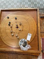 Full view of wooden crokinole board with discs set up and bag of spare pucks