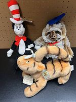 Three plush toys grouped together: Tigger, Cat in the Hat, graduation sloth
