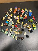 Overall view of minifigures, accessories, battle droid parts and watch on black surface