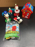 Group shot showing metal tin, sealed bag, and loose Snoopy figures