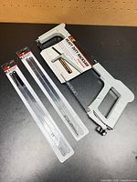 Hacksaw frame with two packs of blades laid out on table