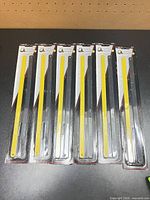 Front view of six sealed packs of hacksaw blades