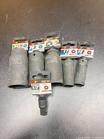 Group of five deep sockets and one adapter showing sizes and condition