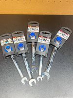 Five packaged ratcheting wrenches laid out on surface