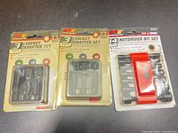 Front view of all three packaged sets: two W1390 socket adapter sets and one W473 nutdriver/bit set