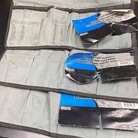 Front view of folded gray bucket organizers showing pocket layout and attached retail cards