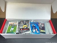 Open long storage box filled with football trading cards, several sleeved cards visible on top