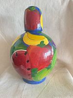 Decanter assembled with stopper showing multicoloured fruit design on blue background