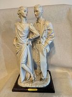 Full view of standing couple figurine on wood base