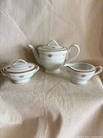 Front view of teapot, creamer and sugar bowl showing overall design