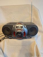 Front view showing speakers, bass reflex port, cassette deck, CD lid, antenna and AC cord