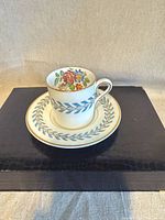Teacup on saucer showing floral interior, blue laurel band, gold trim