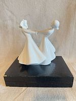 Front view of porcelain figurine showing two women holding hands