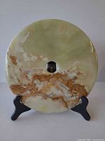 Front view of round green onyx/agate disk on black wooden easel